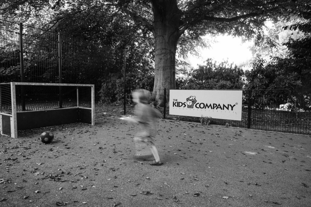 Kind speelt voetbal op het buitenterrein van The Kids Company BSO in Veldhoven